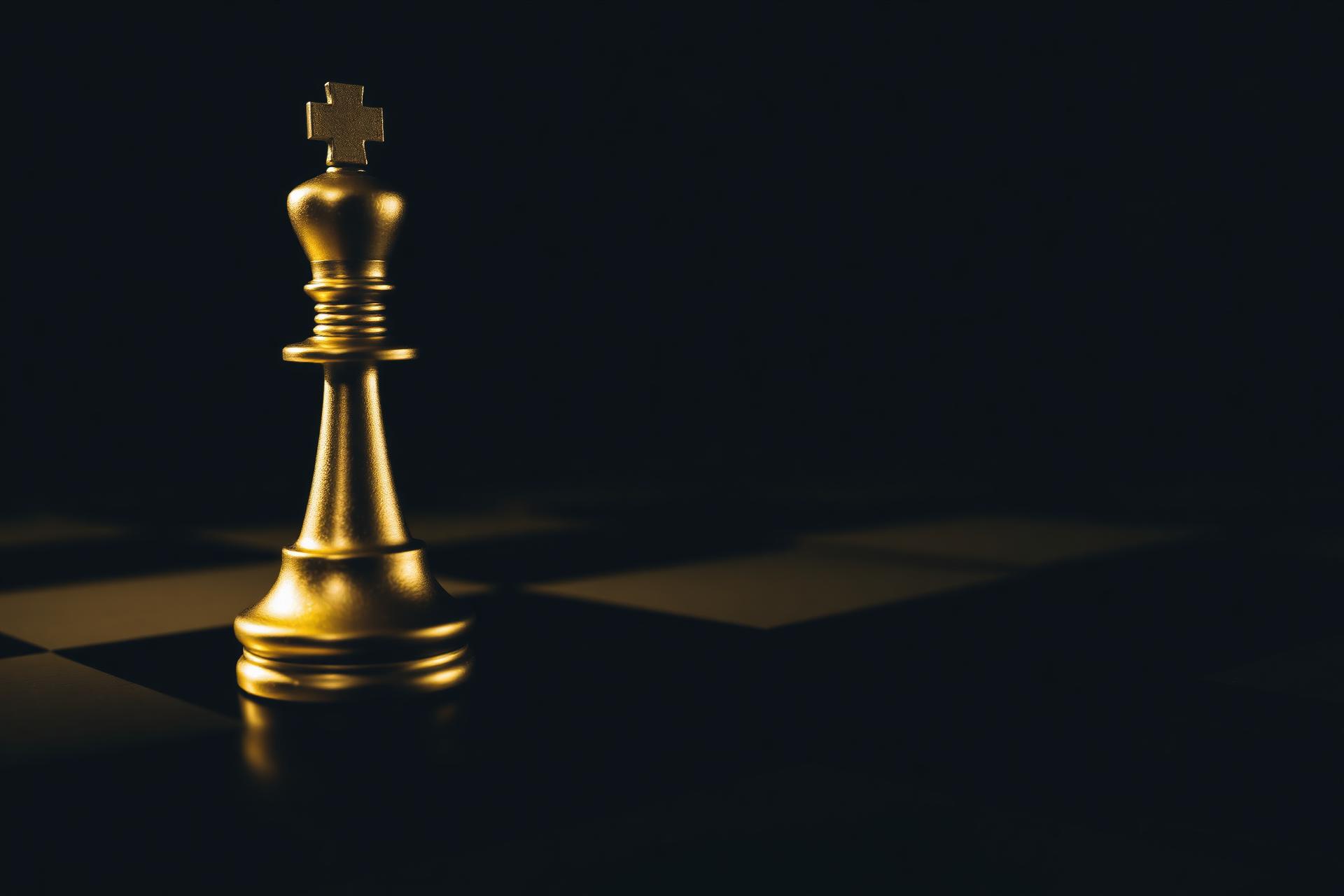 Golden chess king piece on dark board
